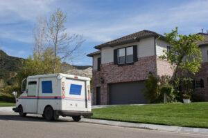 A USPS truck parked in front of a house, leaving nearby residents to wonder about what happens if you get in an accident with a mail truck.