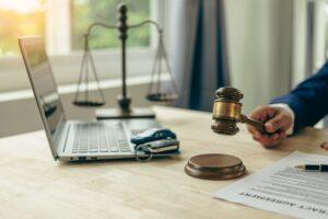Lawyer, judge's gavel and miniature car as symbols of auction or court action against driver who got into an accident and received car insurance money on the table.