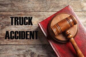 Truck accident law. Judge's gavel and book on wooden table, top view.