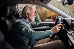 Shocked old man having car car accident in traffic on city street downtown.