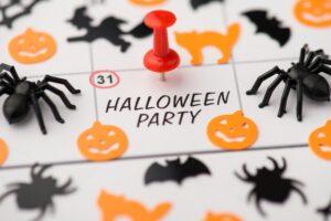 Above photo of label date 31 october red pin with inscription halloween party and decor as pumpkin witch spiders spiderweb cat and bats isolated on the calendar background