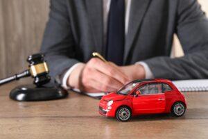 Auto accident law. Man working at wooden table indoors, focus on toy car.