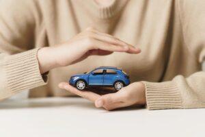 Woman hand Protecting blue Car, symbol of Car Insurance and vehicle protection concept.