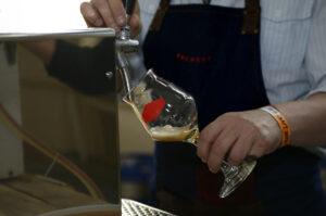 Bartender’s hands pouring a glass with draught beer from a beer tower.