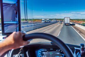 View from the driving position of a truck of a three-lane highway crowded with vehicles.