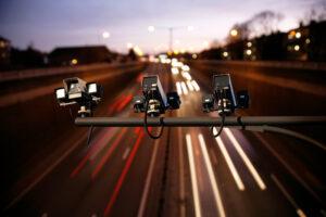 Speed camera monitoring busy traffic road at night.